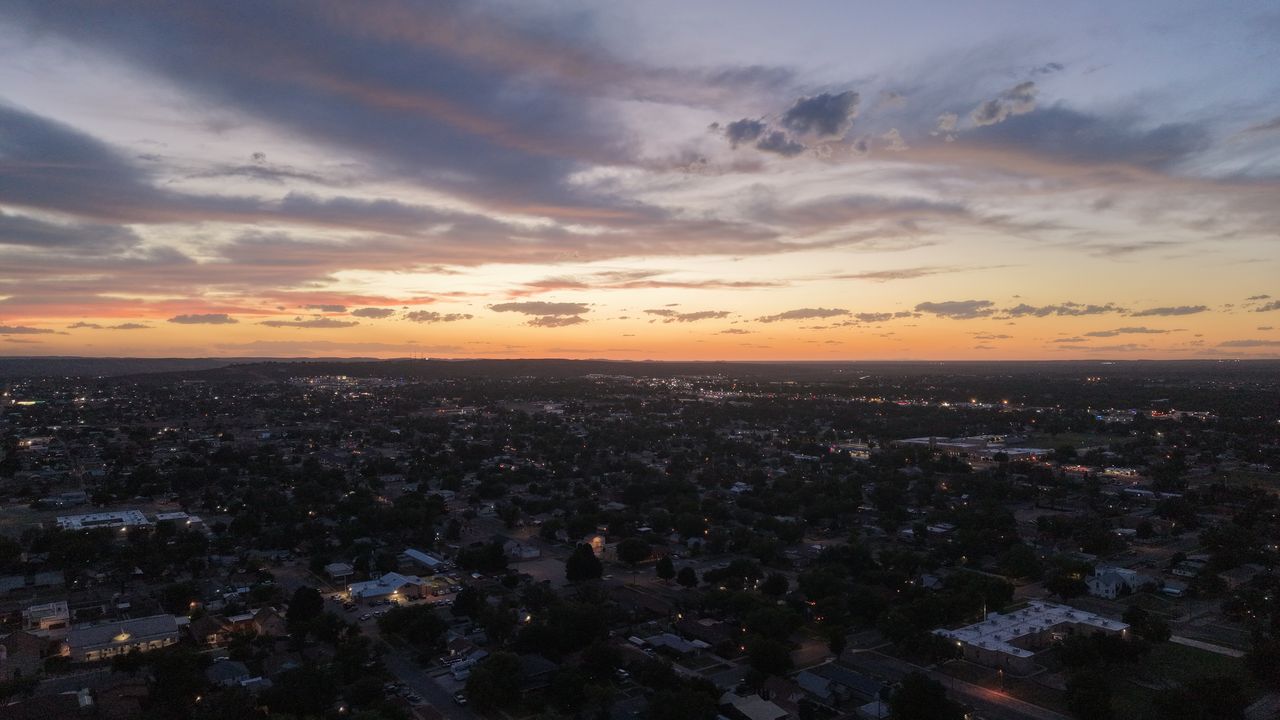 Sunset over Carlsbad, New Mexico neighborhoods from the air, with the Guadalupe Mountains on the western horizon